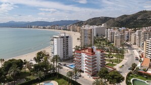 A coastal cityscape with high-rise buildings, a beach, and a mountainous backdrop. - FLORAZAR 2, VI-15-A (Cullera)