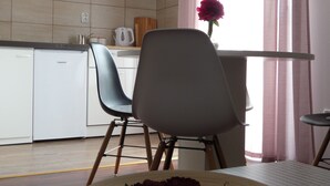 A kitchen with white cabinets, a white refrigerator, a dining table with chairs, and a flower vase on the table. - Apartment Jan, Pakaljski odvojak 4, 53220 Otočac, Licko-Senjska county, Croatia (Otočac)