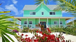 A two-story house with a green exterior and a porch.