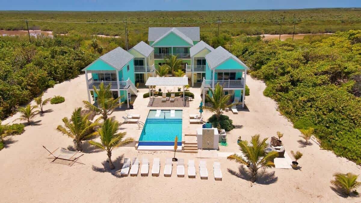 Een resort met een groot zwembad, diverse gastenkamers en een zandstrand.