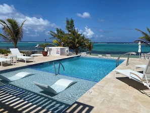 Une piscine avec des chaises longues et vue sur l’océan.