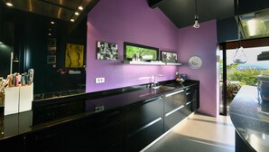 Una cocina moderna con encimeras negras, una pared de acento morada y un amplio ventanal con vistas panorámicas.