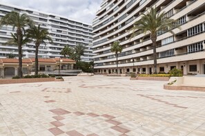 A large, multi-story hotel with a central courtyard featuring palm trees and a tiled floor.