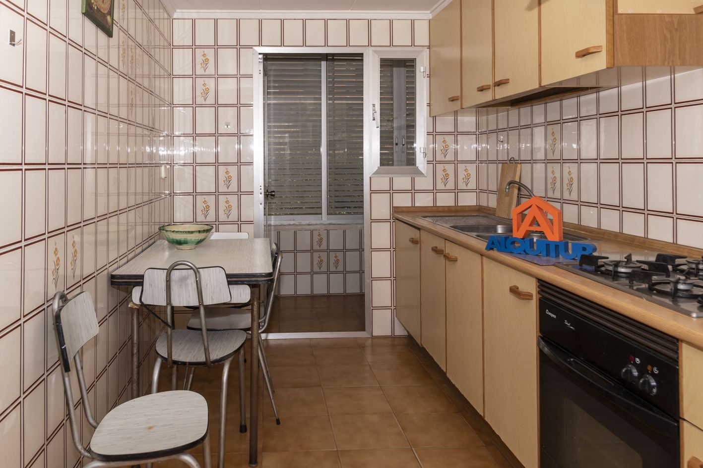 Una cocina compacta con una mesa de comedor, sillas, estufa y armarios.