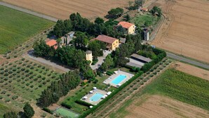 Vista aérea de una propiedad con piscina, cancha de tenis y campos circundantes.