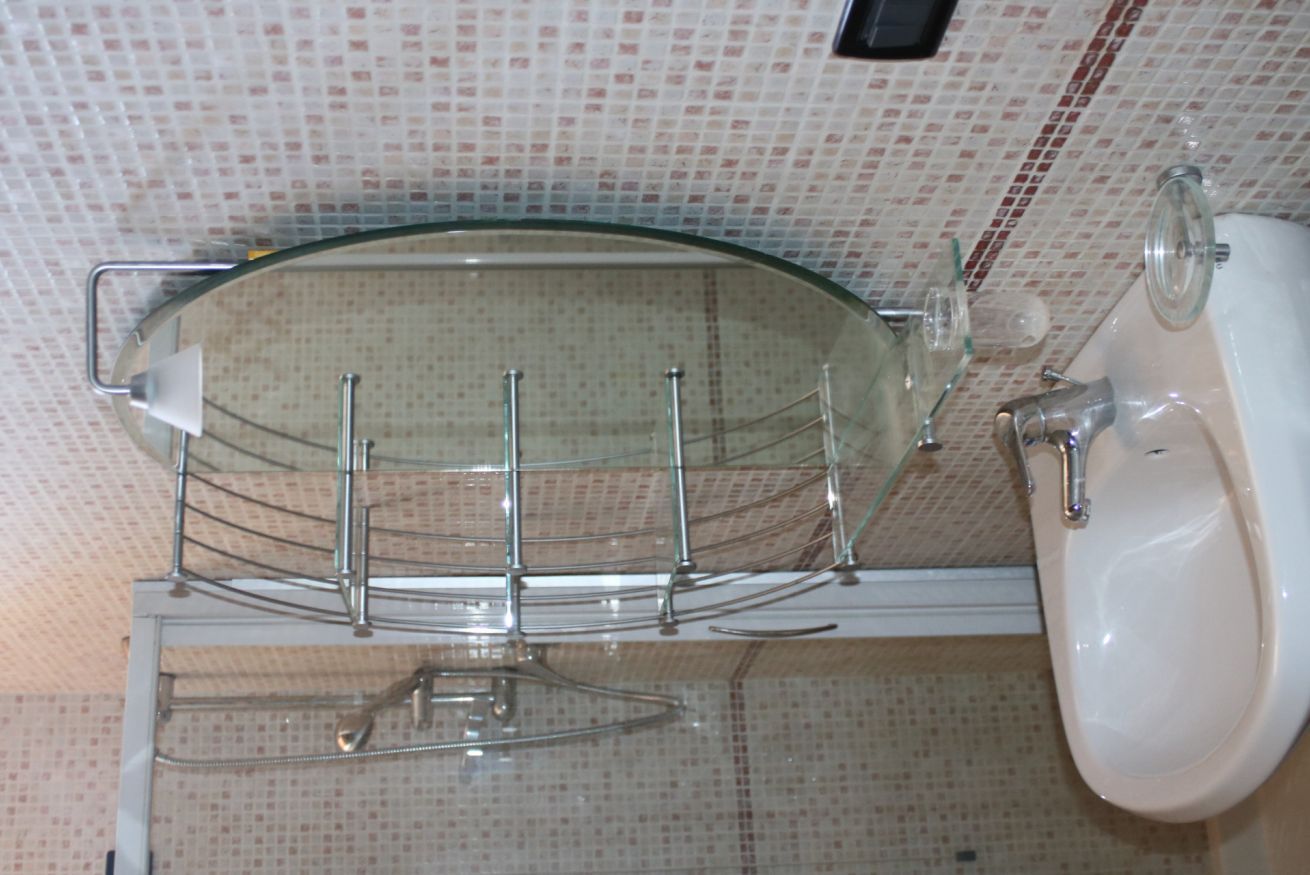 A bathroom with a glass shower enclosure, a white sink, and a tiled wall.