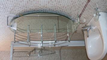 A bathroom with a glass shower enclosure, a white sink, and a tiled wall.