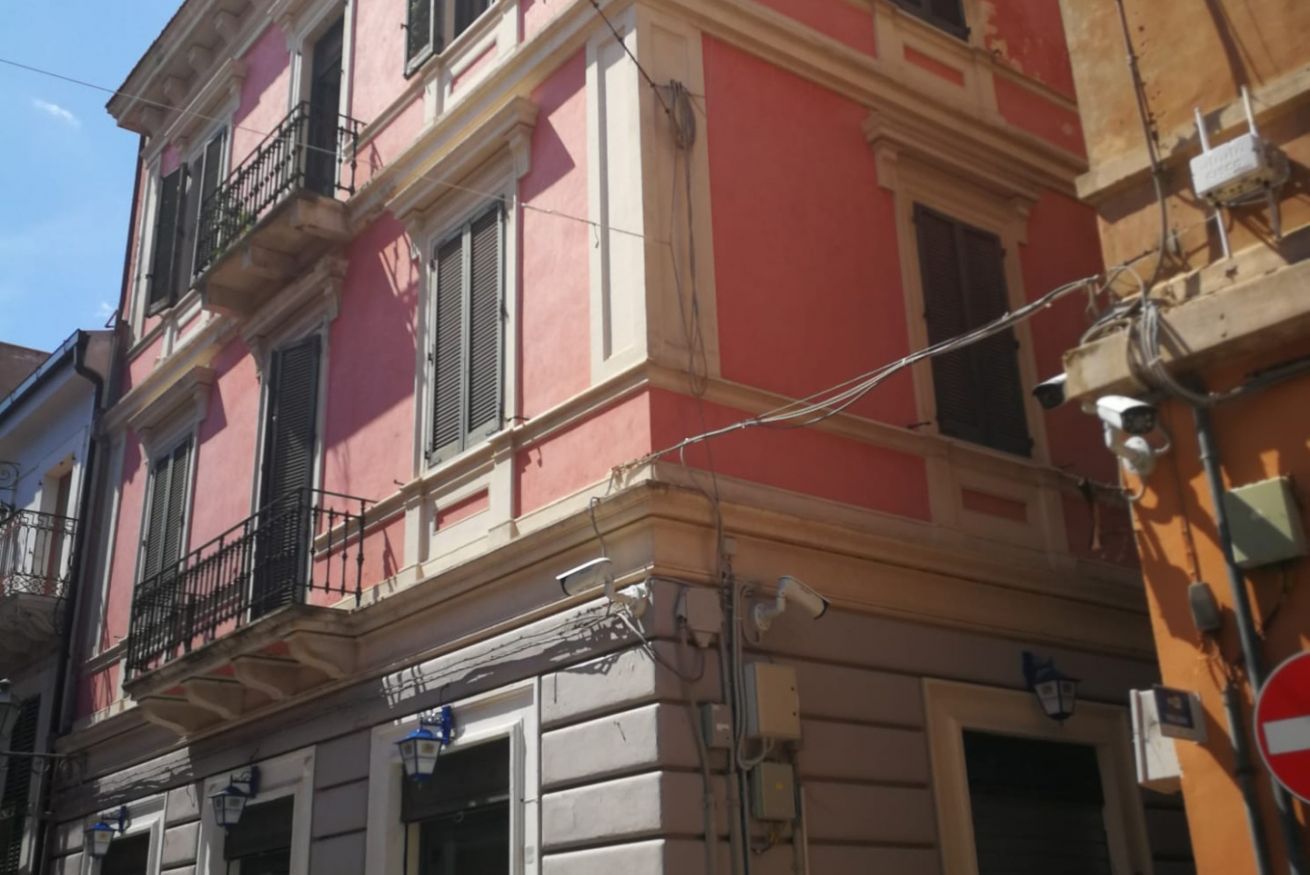 A multi-story building with balconies, a street sign, and visible electrical wiring.