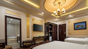 A luxurious hotel room with a large bed, a television, a minibar, and a bathroom visible through an open door. - Sepia Hotel DaLat (Xuan Huong - Da Lat)