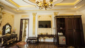 A luxurious room with a chandelier, a large mirror, a television, and a wardrobe. - Sepia Hotel DaLat (Xuan Huong - Da Lat)