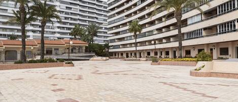 Un gran hotel de varios pisos con un patio central que cuenta con palmeras y piso de baldosas.