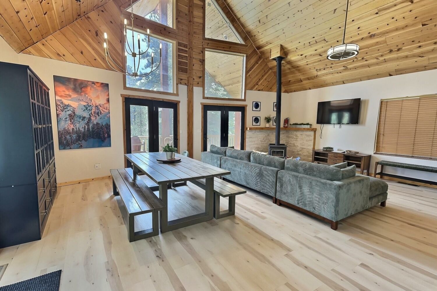 A spacious living area with a wooden ceiling, large windows, a fireplace, and a sofa.
