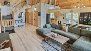 Un vaste espace de vie doté d’un plafond en bois, d’un escalier et d’un grand canapé.