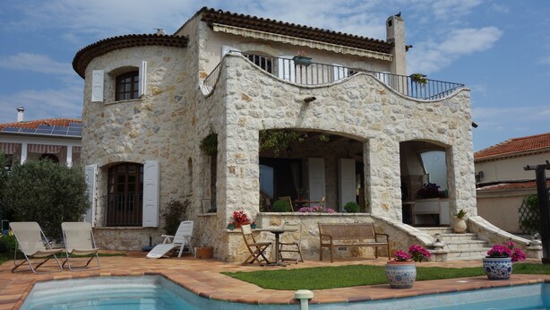 A stone villa with a swimming pool, outdoor seating, and a balcony with potted plants. - Charming Provencal farmhouse, nice and well located, with pool (Cagnes-Sur-Mer)