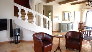 A spacious living area with a staircase, leather armchairs, a dining table, and a television. - Charming Provencal farmhouse, nice and well located, with pool (Cagnes-Sur-Mer)