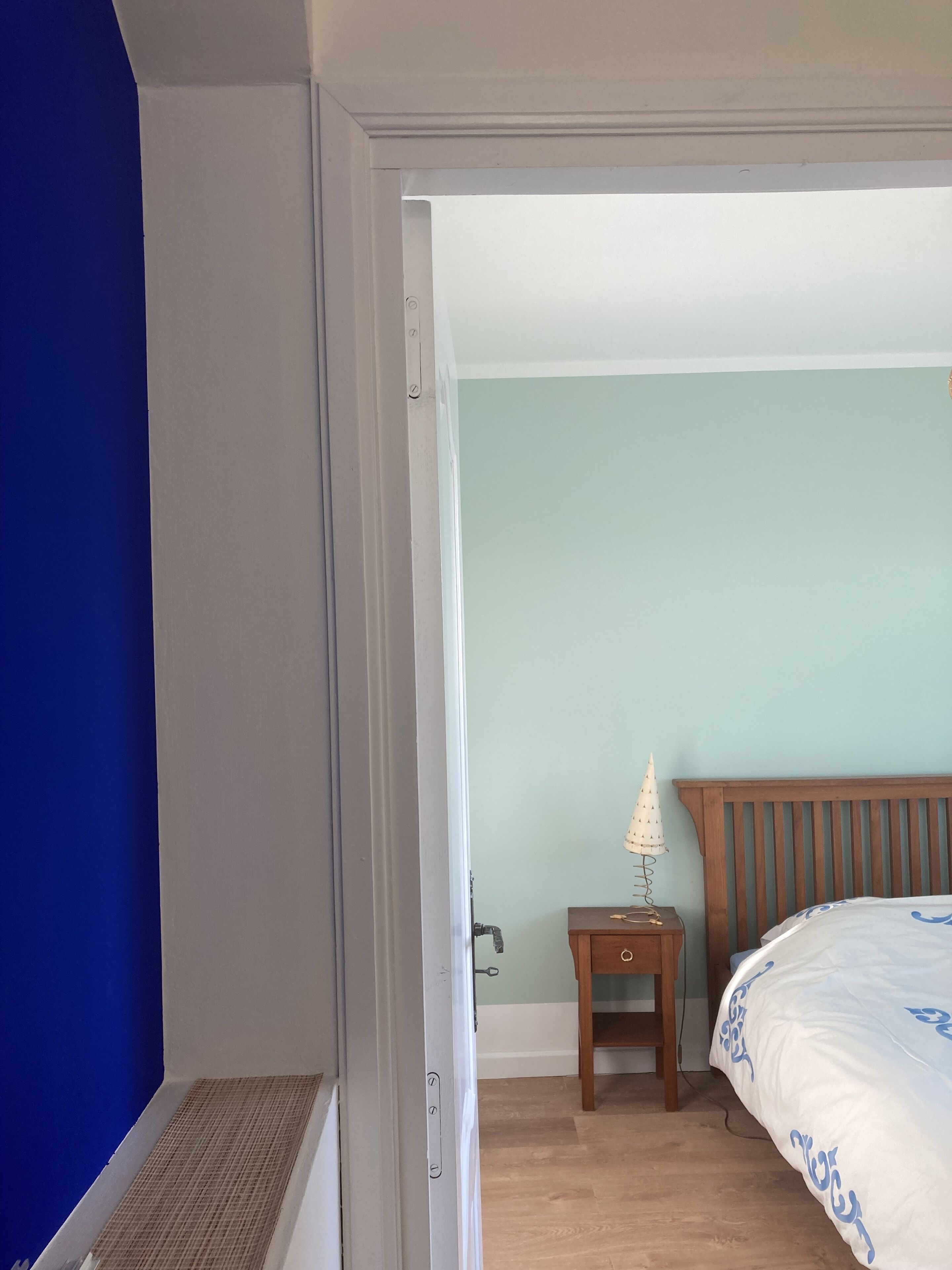 Een slaapkamer met een bed, nachtkastje, lamp en een radiator.