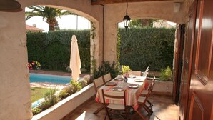 An outdoor patio with a table set for dining, surrounded by a garden and a pool. - Charming Provencal farmhouse, nice and well located, with pool (Cagnes-Sur-Mer)