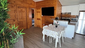 Uma cozinha acolhedora com paredes de madeira, uma mesa de jantar com cadeiras e uma geladeira.