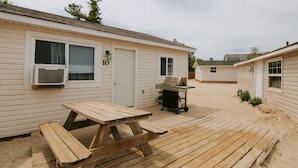 A wooden deck with a picnic table, a grill, and a house with a number 10 sign.