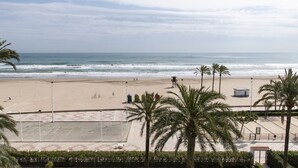 A beach with a clear view of the ocean, palm trees, and a sandy area with a small structure.
