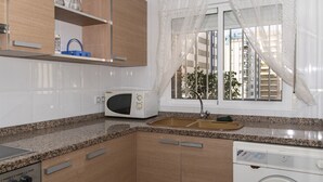 A compact kitchen with a microwave, sink, and washing machine.