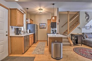 Kitchen with island, sink, and living area, featuring a staircase to the upper level.