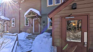 Una casa de dos pisos con un porche delantero cubierto de nieve y escalones que conducen a la puerta.