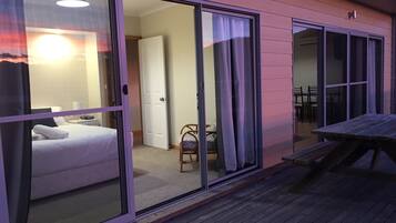 A bedroom with a bed, a chair, and a table on a wooden deck.