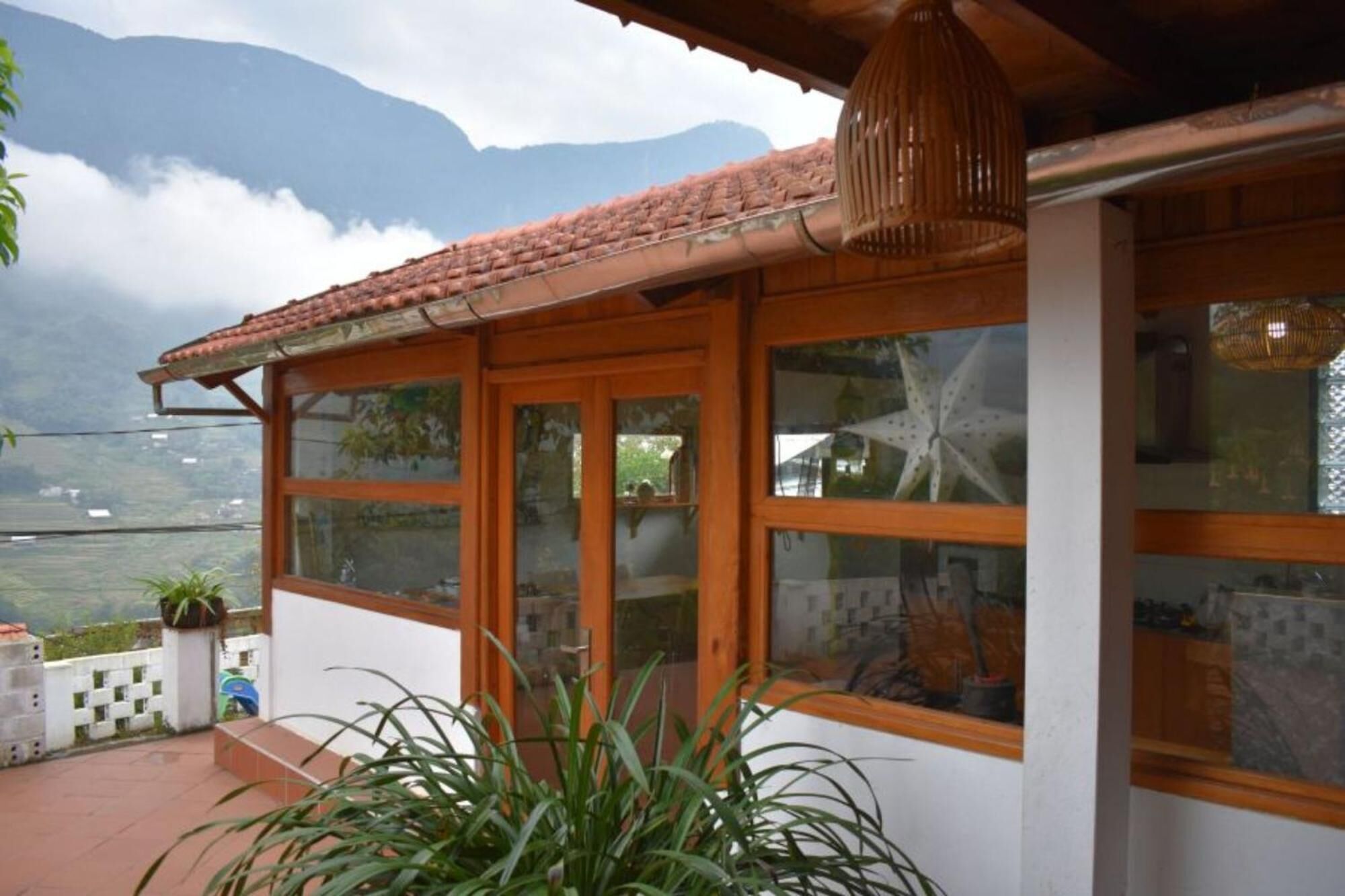 Una habitación con ventanas amplias, techo de tejas y vistas a montañas.