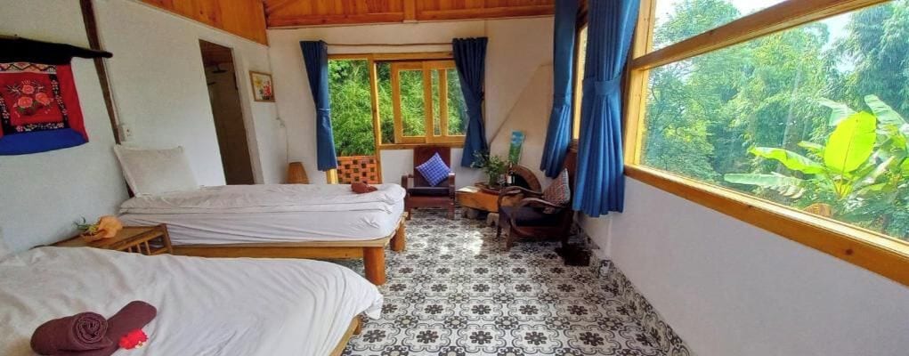 Habitación con dos camas, una ventana con cortinas, una silla y vistas a zonas verdes.