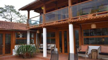 A two-story building with large glass windows, wooden columns, and outdoor seating.