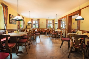 A spacious dining area with multiple tables and chairs, large windows with curtains, and hanging pendant lights. - Double room large (with balcony/terrace) - Brauerei-Gasthof Pfister (Eggolsheim)