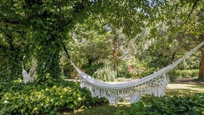 A hammock in a lush garden with dense foliage and trees. - La Tronquiere (Lacropte)