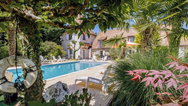 A pool area with lounge chairs, a lifebuoy, and a house in the background. - La Tronquiere (Lacropte)