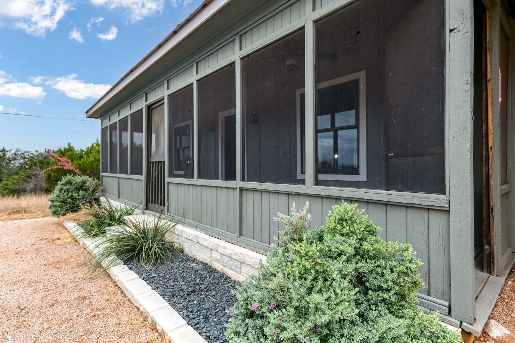 A single-story building with a grey exterior, large windows, and a covered porch area.