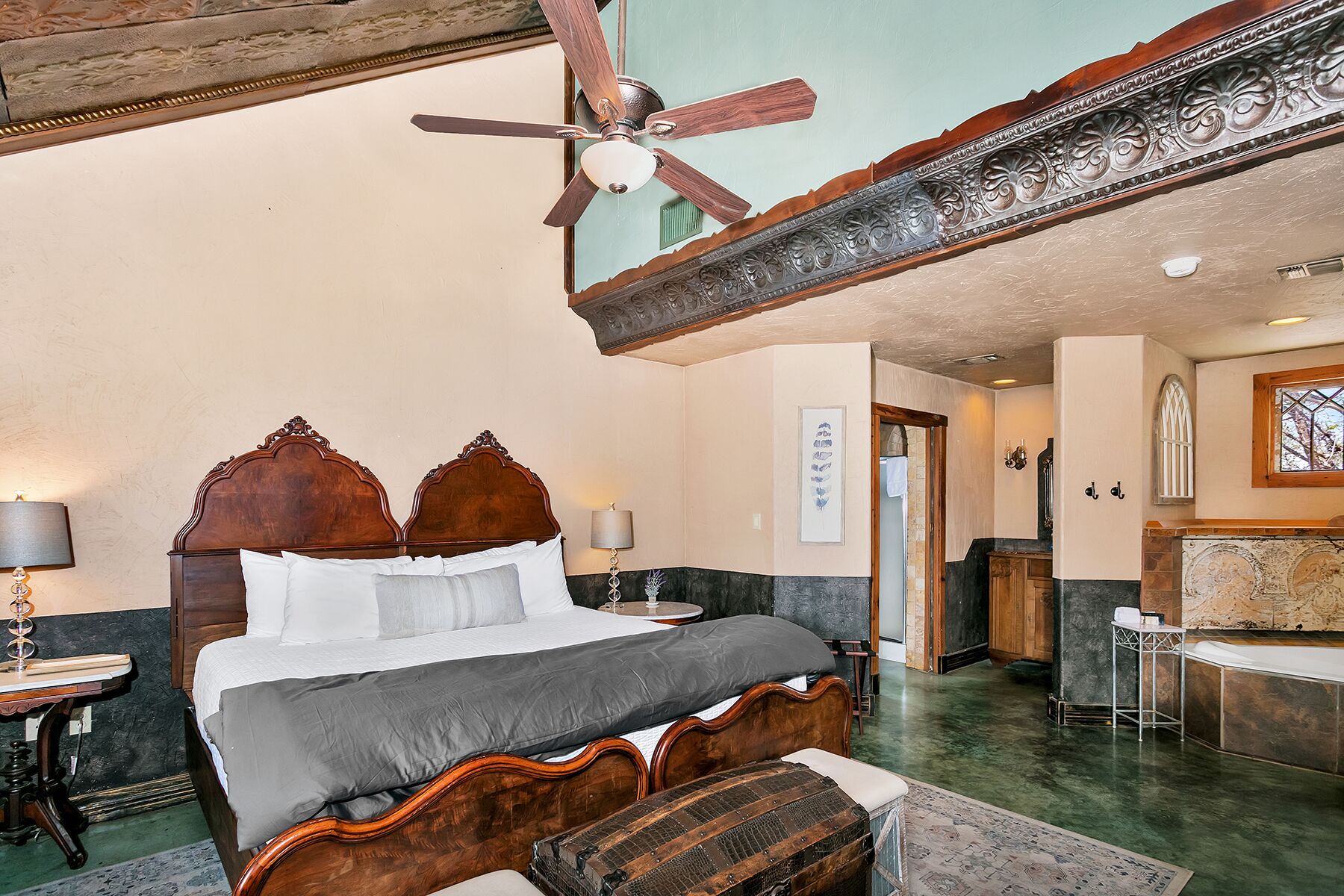 Ein geräumiges Schlafzimmer mit einem großen Bett, einem Deckenventilator und Blick ins Bad.