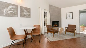 Una sala de estar moderna con chimenea, dos sillones de cuero marrón, una mesa redonda blanca y dos obras de arte colgando en la pared.