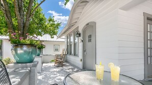 A patio with a table, two chairs, a potted plant, and two glasses of lemonade.