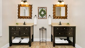 A bathroom with two sinks, dark wooden cabinets, and a decorative mirror with light fixtures.