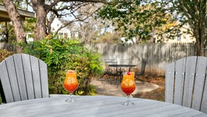 Twee drankjes op een houten tafel, met een houten hek en stoelen op de achtergrond.