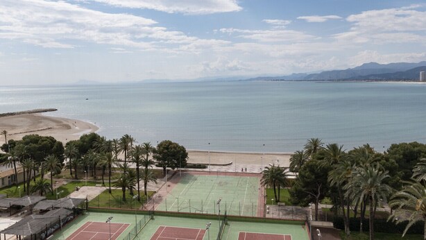 Une vue sur la côte, avec une plage, des courts de tennis et des palmiers.