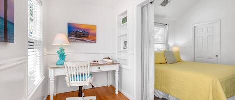 A bedroom with a bed, a desk, and a chair.