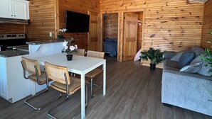 Un intérieur de type cabine, compact et fonctionnel, comprenant une cuisine, un coin repas et un espace salon.