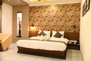 A modern bedroom with a large bed, wooden headboard, bedside lamps, and a decorative wall panel.