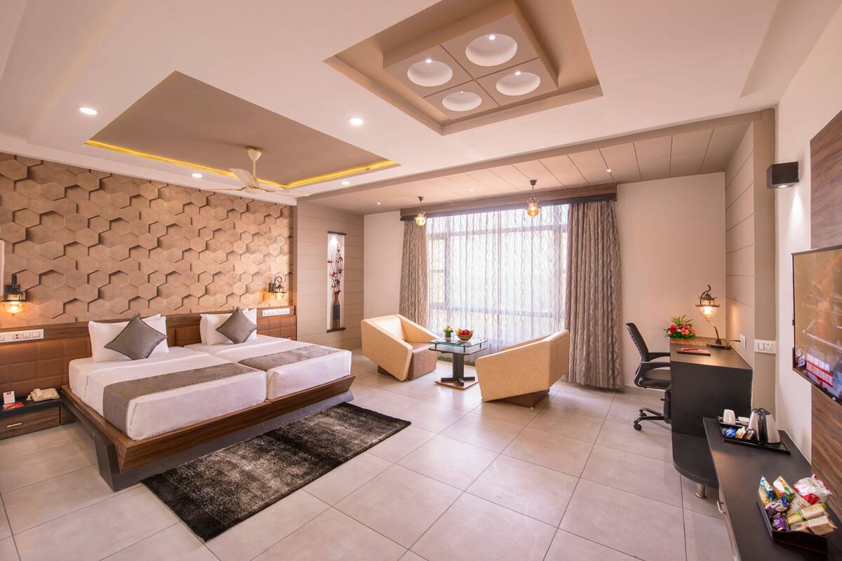 Quarto de hotel moderno com uma cama grande, uma escrivaninha, uma cadeira e uma televisão.