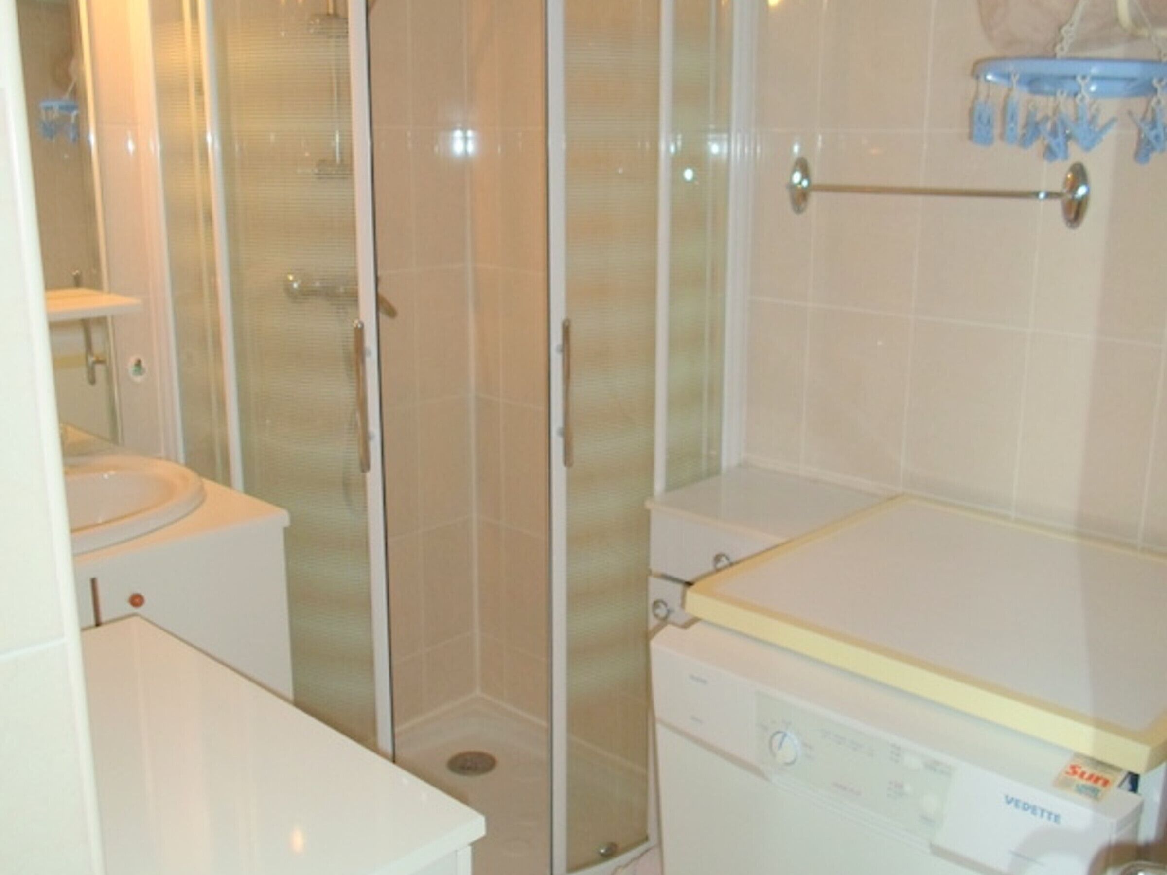 Un baño con inodoro, cabina de ducha y lavadora.