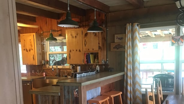 Una cucina rustica con mobili in legno, un'isola centrale con sgabelli e un'area pranzo con tavolo e sedie.