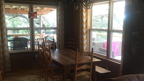Un'accogliente sala da pranzo con tavolo e sedie in legno, un lampadario e ampie finestre che offrono vista sull'esterno.