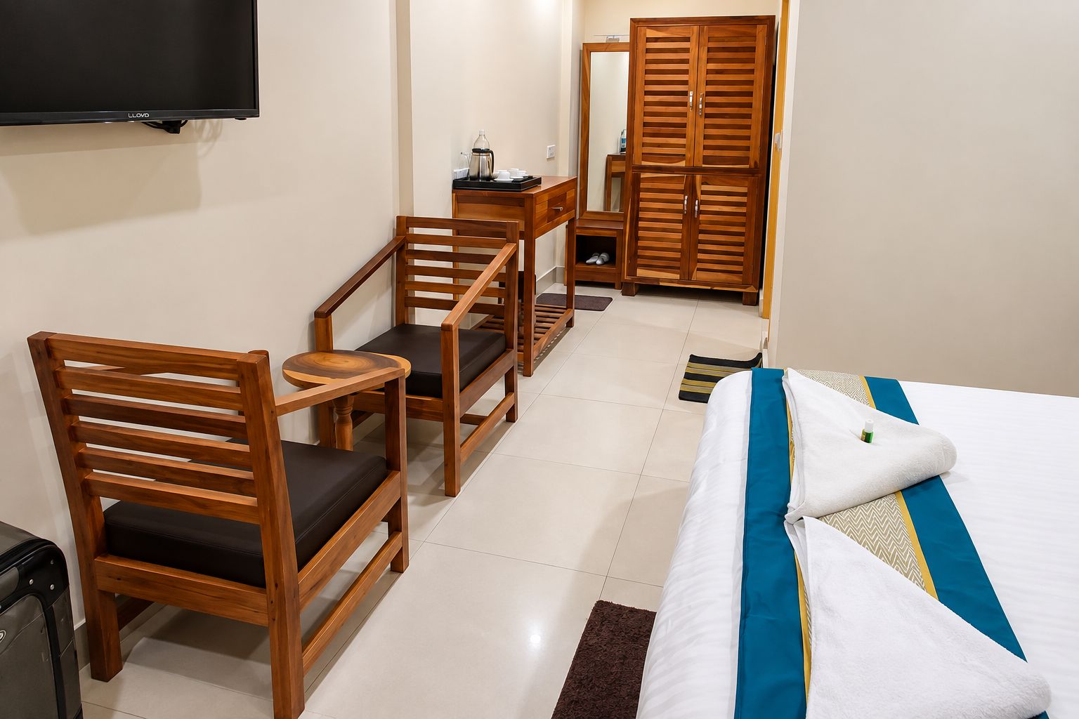 Une chambre d’hôtel comprenant un lit, un bureau, deux chaises, une télévision et une armoire.