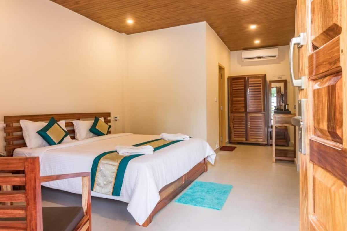 A bedroom with a wooden bed frame, white bedding, and a wooden wardrobe.